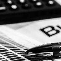 black and white photo of a calculator and fancy pen sitting on top of some business papers on the financial tools page